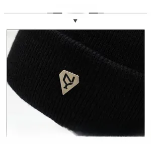Detailed close-up of black ribbed knit beanie featuring a shield-shaped metal emblem