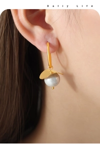 Close-up of elegant gold plated pearl drop earrings featuring a round white pearl on model