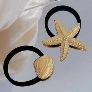 Golden starfish and shell hair ties with black elastic band on satin background