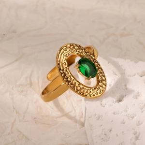 Dettaglio dell'anello vintage dorato con zircone verde smeraldo su pietra bianca ruvida