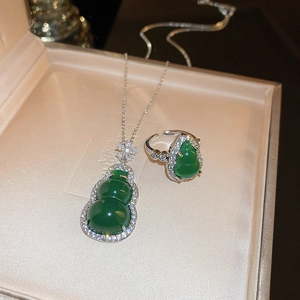 Macro shot of green resin gourd pendant and ring set with zircons in a beige jewelry box