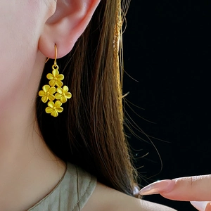 Detail of matte 18K gold flower drop earrings worn by model on black background