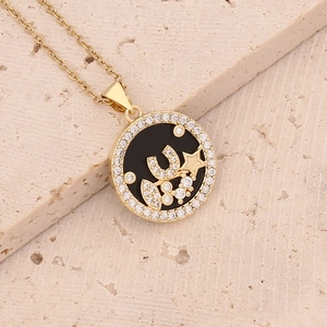 Detail shot of a gold round pendant with black enamel inlay and zircon crescent moon stars