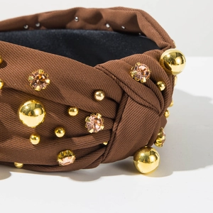 Macro detail of brown twisted headband with polished gold beads and pink rhinestones