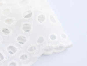 Dettaglio macro dell'elegante tessuto in pizzo bianco idrosolubile con ricamo fine