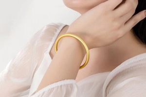 Detailed view of matte gold solid bangle on a model showing classic round design
