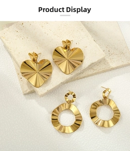Detail showing golden heart-shaped earrings and wavy round hoops on a stone display