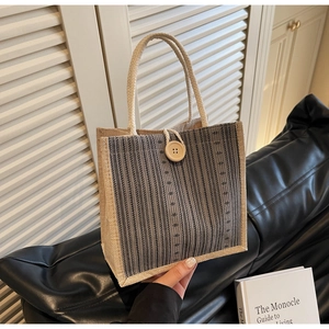 Detail of linen tote bag featuring grey striped weaving and round braided handles
