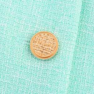 Détail du tissu en tweed vert menthe avec bouton doré rond en relief élégant