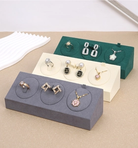 Three-slot velvet jewelry display stands in green, cream and grey on white wave prop