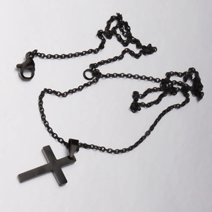 Detailed close-up of a minimalist black metal cross pendant on a sleek chain necklace