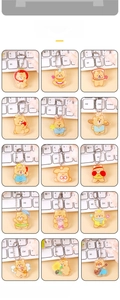 Grid display of fifteen assorted cute cartoon bear acrylic keychains on a white keyboard