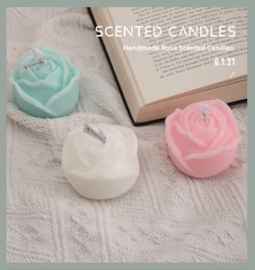 Detailed view of rose shaped scented candles in blue, white, and pink on soft knit fabric