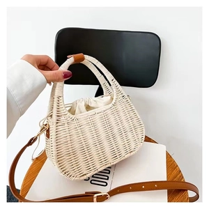 Detail of white woven rattan crossbody bag with leather handle and drawstring closure
