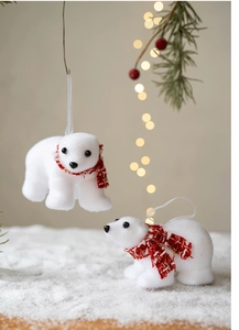 Detail view of two flocked white polar bear ornaments with red plaid scarves on snowy pine