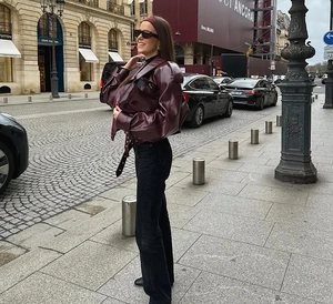 Street style view of a burgundy glossy leather jacket with waist belt and retro lapels