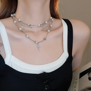 Detail of multi-layer pearl necklace with a zircon-studded silver cross pendant on a model