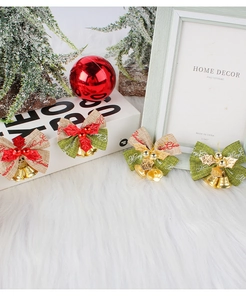 Set of four rustic burlap Christmas bow ornaments with twin bells on white plush surface