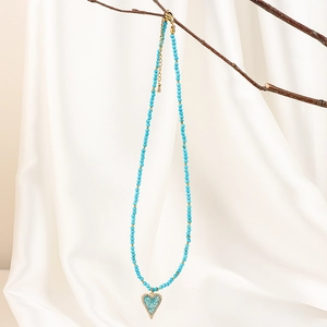 Detailed shot of a blue heart pendant with white zircons on a beaded necklace