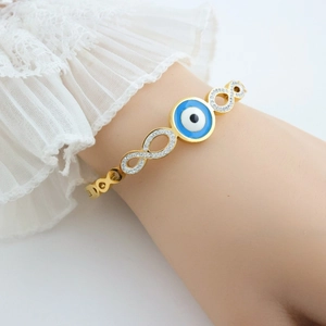 Detail of gold evil eye and infinity symbol bangle with pave zircons and lace cuff