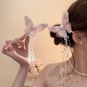 Detail of pink butterfly hair clips with pearl beads and long tassels on model's hair