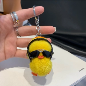 Close-up of a fluffy yellow mink fur duck keychain with a helmet and black sunglasses