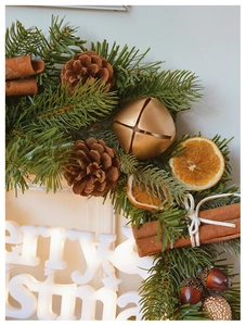 Close-up of Christmas wreath with pine needles, cinnamon sticks and glowing LED sign
