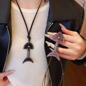 Close-up of leather fishbone pendants with metallic accents in black and brown colors