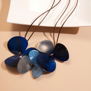 Detail of blue acrylic triple-leaf flower charms on double-layer wax cord necklace