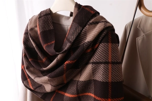Close-up of cashmere-feel scarf with orange and khaki plaid pattern on brown base