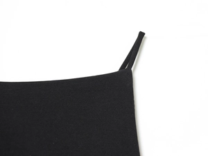 Gros plan sur les coutures et la texture du tissu d'un haut noir à nœud au dos