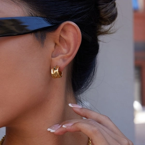 Detail of gold-plated irregular C-shape hoop earrings with hammered texture on model