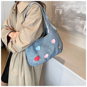 Sac seau en denim bleu avec patchs cœurs colorés sur un mannequin en trench kaki