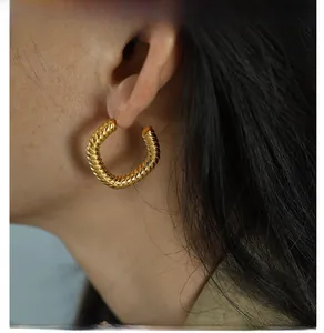 Detail of a vintage-style gold twisted rope hoop earring worn by a model in close-up