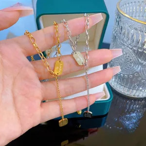 Detail of gold and silver chunky link necklaces featuring a Lucky tag and square charm