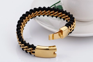 Macro detail of men's braided leather bracelet with polished gold-tone metal fold-over clasp