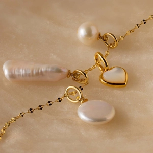Close-up of gold 18K plated stainless steel necklace with pearls and heart shell pendant