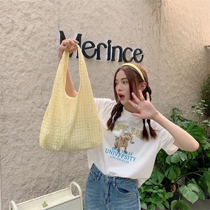 Detail of yellow checkered canvas tote bag worn by model in a casual street style look