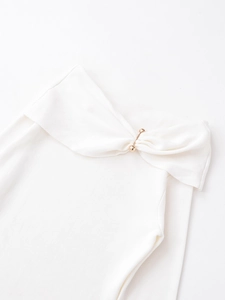 Detail of off-white ribbed knit top featuring a twisted design with a gold metal accent