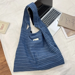 Blue and white striped knit tote bag styled with a laptop on a soft white bedspread