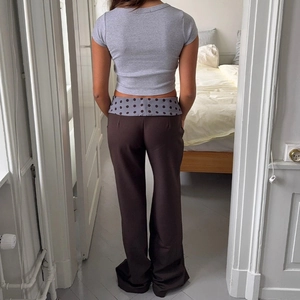 Rear view of low waist brown trousers with blue polka dot fold-over waistband detail