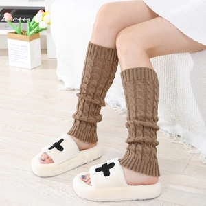 Detail of coffee brown cable knit leg warmers with ribbed cuffs in a cozy indoor setting