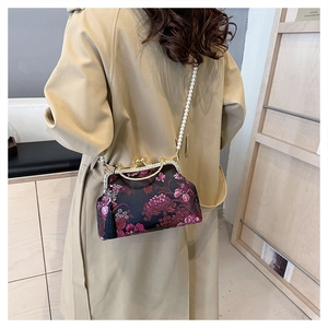 Floral shell bag with pearl strap and tassels worn over a beige trench coat
