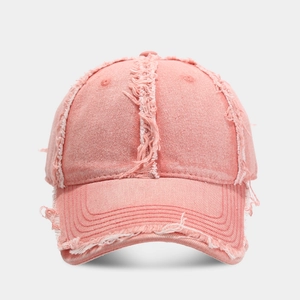 Gros plan sur une casquette en jean vieilli rose corail avec bords effilochés