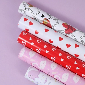 Five rolls of decorative wrapping paper with heart, swan, and whale patterns on purple background