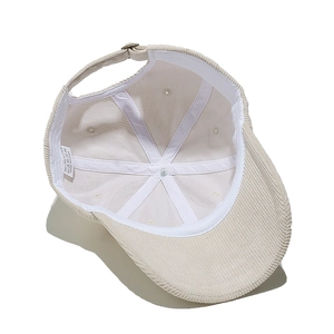 Detail of corduroy baseball cap interior showing 100% polyester label and metal buckle