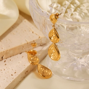 18K gold teardrop earrings with spiral embossed texture on elegant stone display