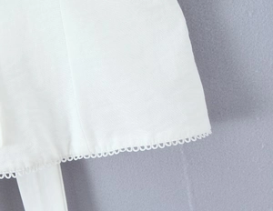 Vue détaillée d'un débardeur blanc avec bordure en dentelle festonnée et texture tissée
