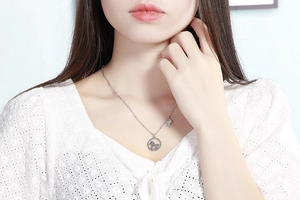 Détail du collier pendentif licorne argenté sur un mannequin en vêtements de dentelle blanche