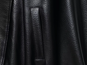 Close-up of black PU leather jacket showing fine grain texture and pocket stitching detail
